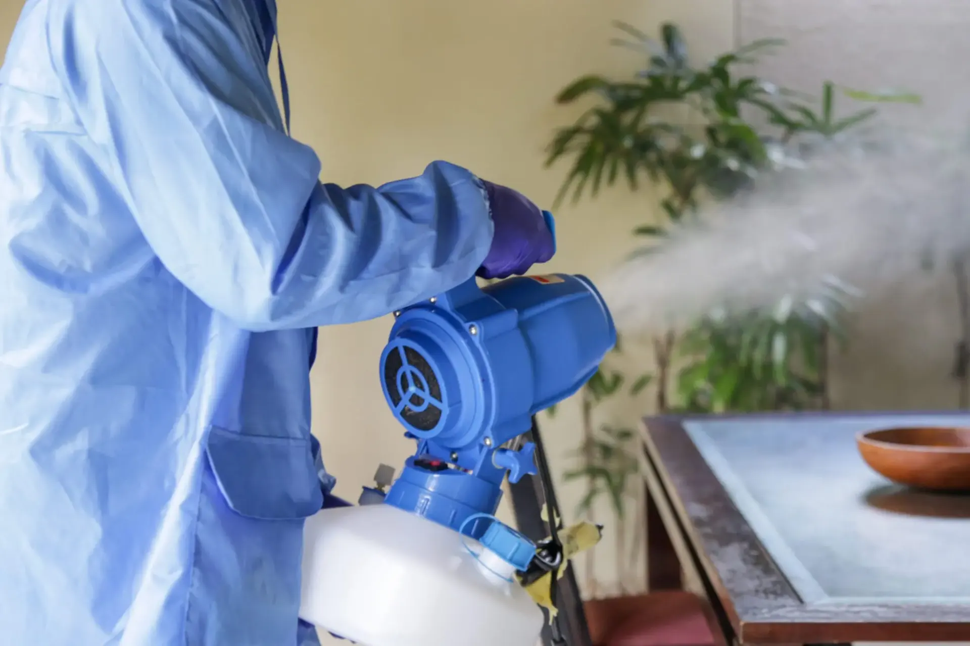 technician fogging room with disinfectant sprayer